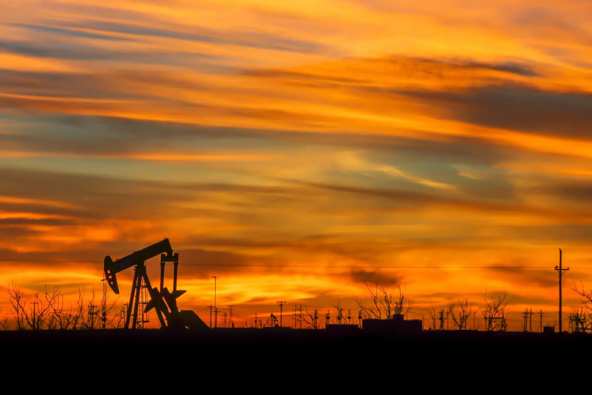 The natural beauty of a vibrant sunrise shines through the industries silhouette of the west Texas oil fields.